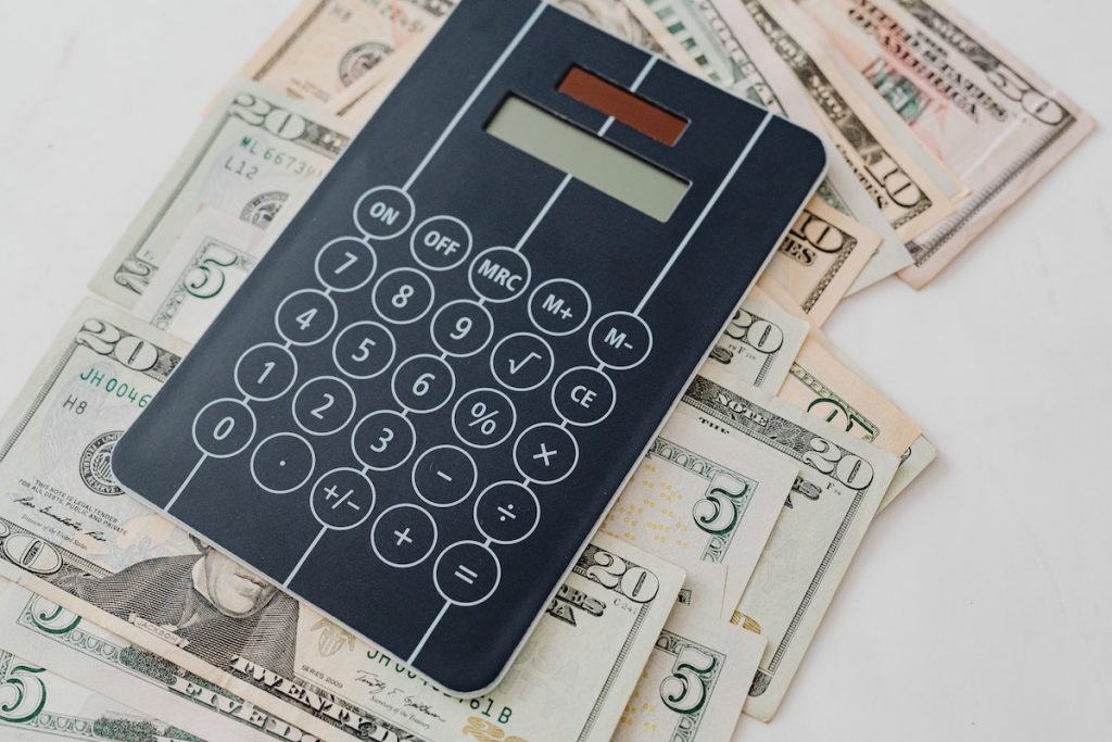 Close-Up Photo of Banknotes Under a Calculator